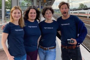 Vier Menschen stehen am Bahngleis und tragen T-Shirts mit der Aufschrift tageswow.de
