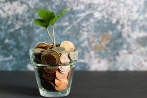 junge Pflanze in einem Glas voller Münzgeld: Sparen fängt früh an