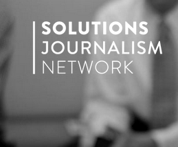 Logo des Solution Journalism Network in weißer Schrift auf schwarzweißem Hintergrund, verschwommen ist ein Arm und eine Krawatte zu erkennen
