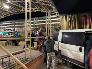 In einer Halle werden Hilfsgüter von einem Transporter in einen Lkw gepackt, um Menschen in der Ukraine zu unterstützen